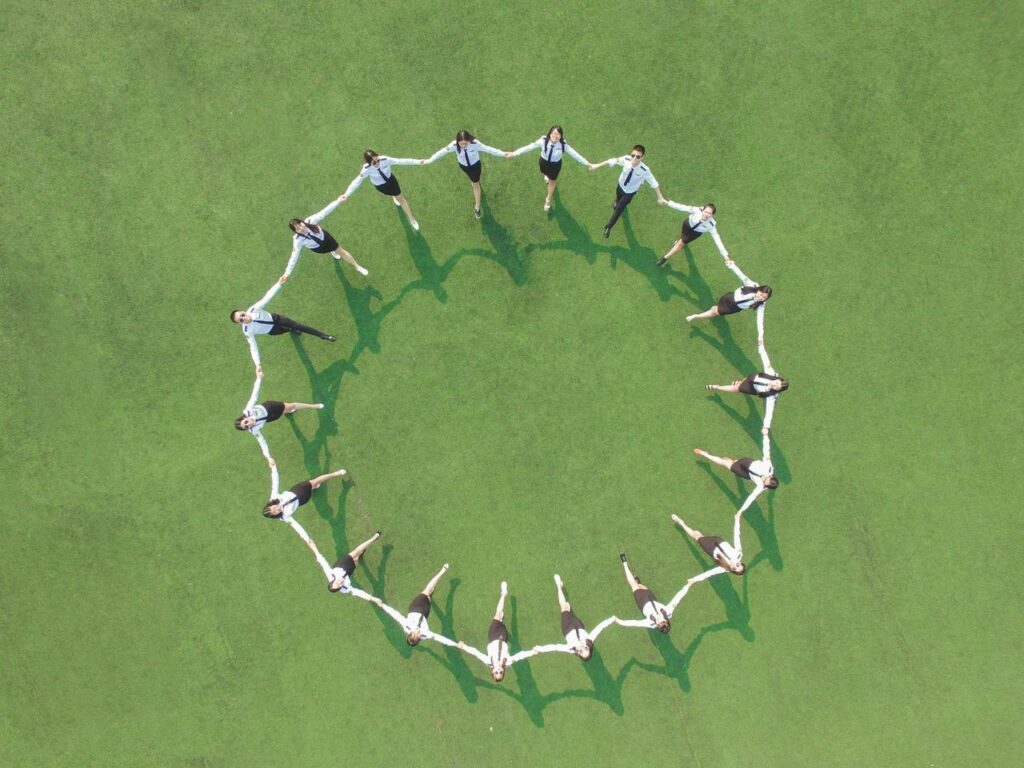 Crafting Captivating Headlines: Your awesome post title goes here Aerial shot of a group forming a circle on a green field, holding hands and connected.