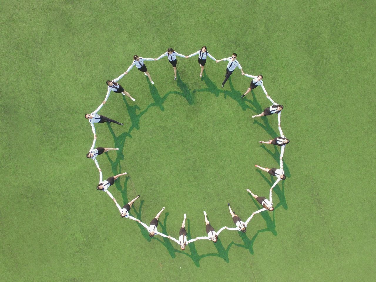Crafting Captivating Headlines: Your awesome post title goes here Aerial shot of a group forming a circle on a green field, holding hands and connected.